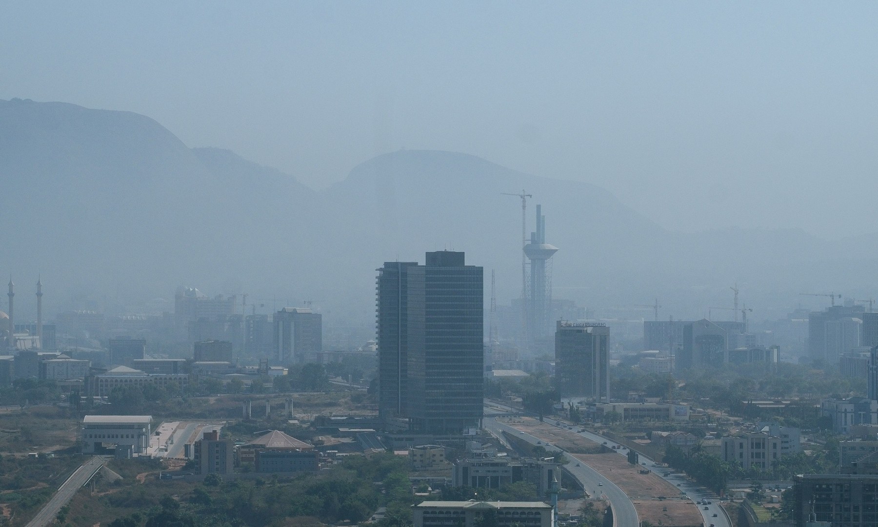 Abuja skyline in fog, with city buildings and mountains in the background